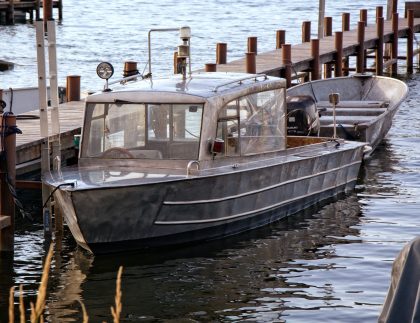 Metal boat moored at a wooden dock