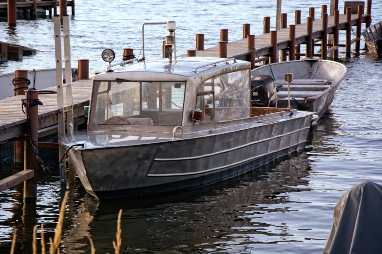 Metal boat moored at a wooden dock