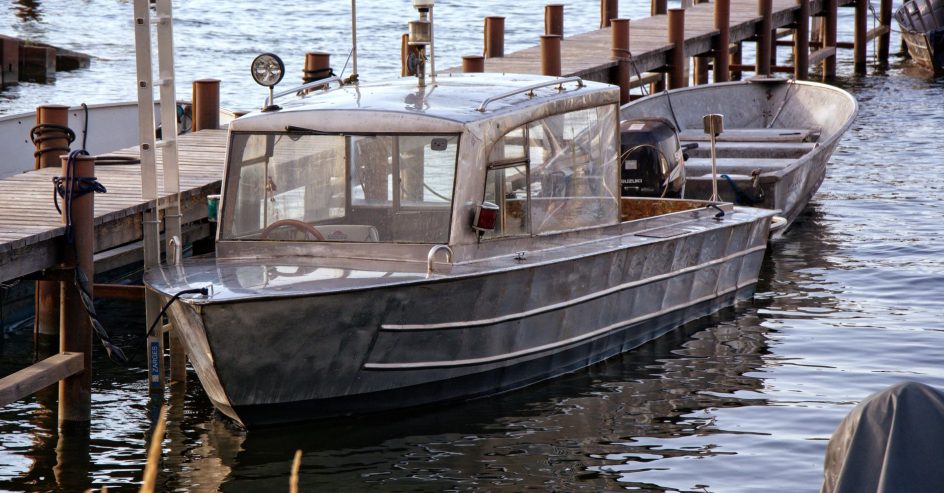 Metal boat moored at a wooden dock