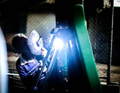 Welder repairing metal fencing with sparks at night