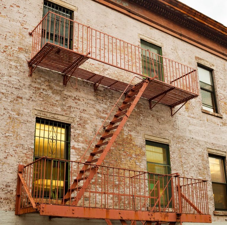 Rusty fire escape landings and ladder outside the windows of an old brick building