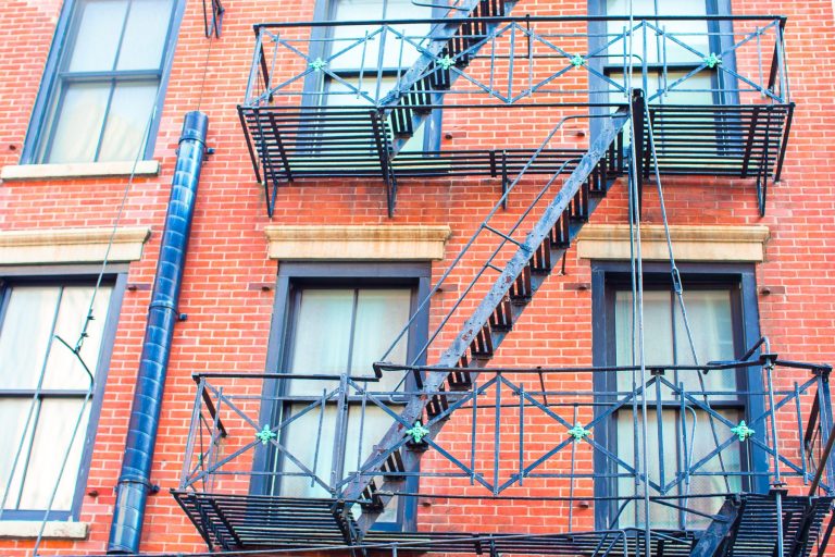 Steel fire escape and stairs on the front of a red brick apartment building