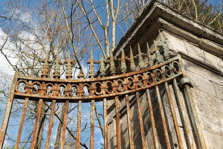 Rusted iron gate attached to a weathered stone pillar